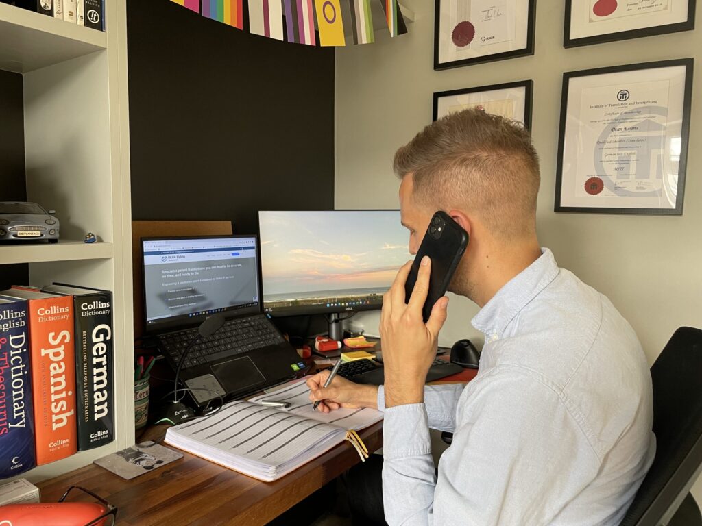 A photo of Dean Evans, patent translator, on the phone at his desk., with his website in the background.